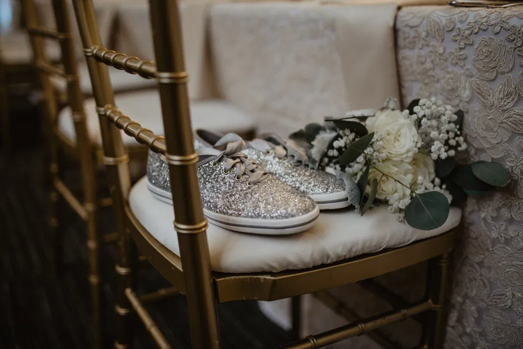 Kate Spade glitter wedding dance shoes to include in your wedding day essentials kit sitting on head table chair photo by New York photographer Jessy Herman Photo