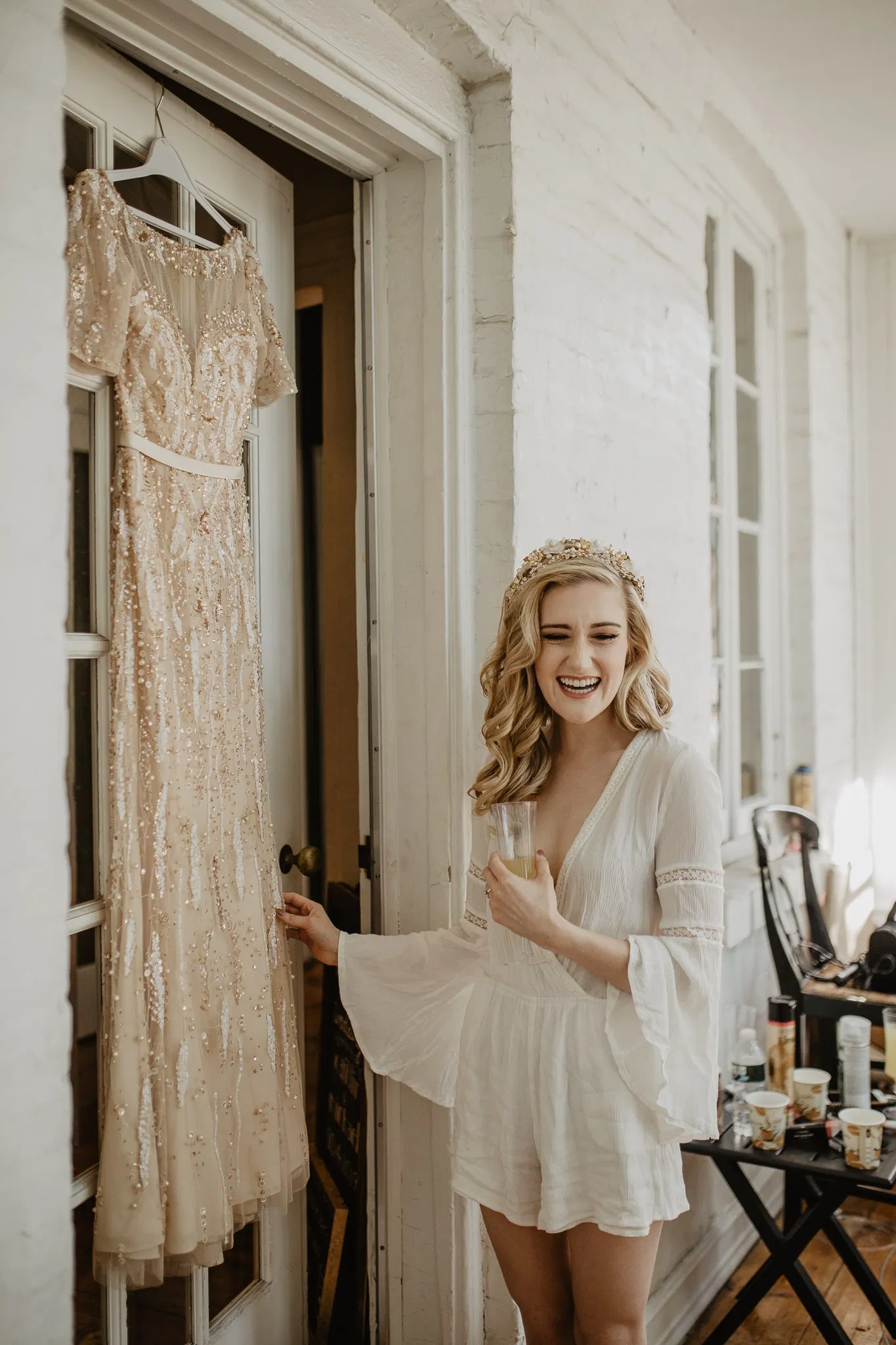 Bride in white rob touching her hanging wedding gown