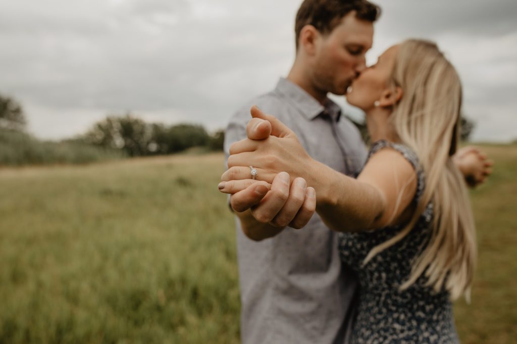 Couple at Tifft Nature Preserve for engagement photos holding hands showing off engagement ring
