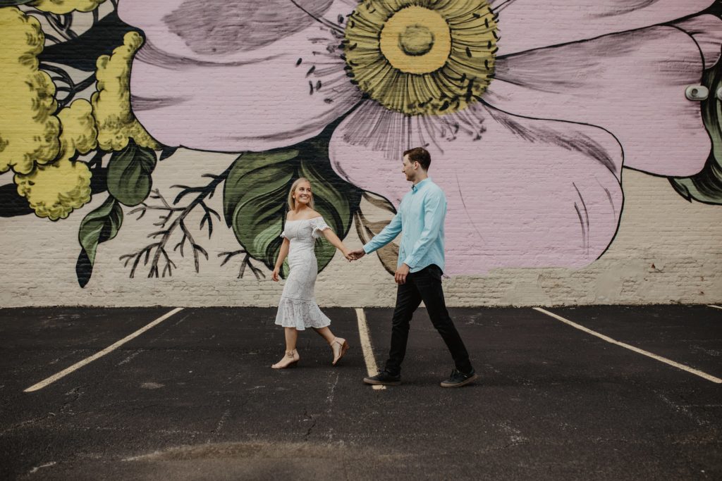 Couple waking holding hands infront of Louise Jones Wildflowers for Buffalo wall mural