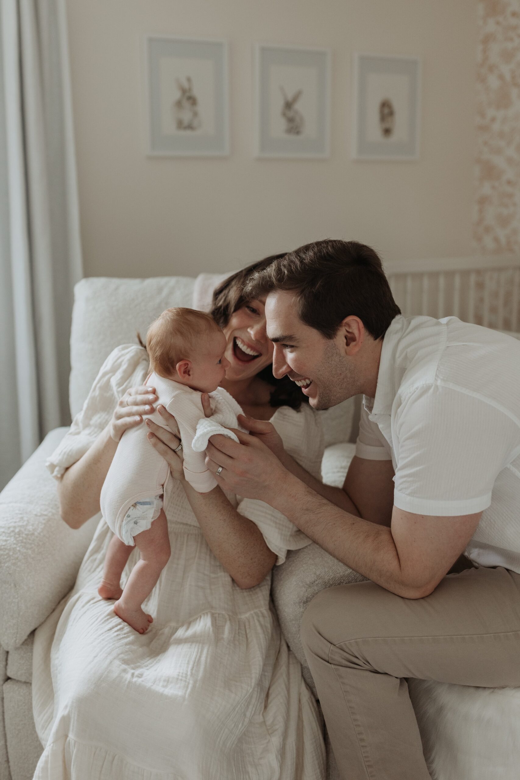 A new mom and dad smile while holding their newborn baby during family photos taken by Buffalo photographer Jessy Herman Photo