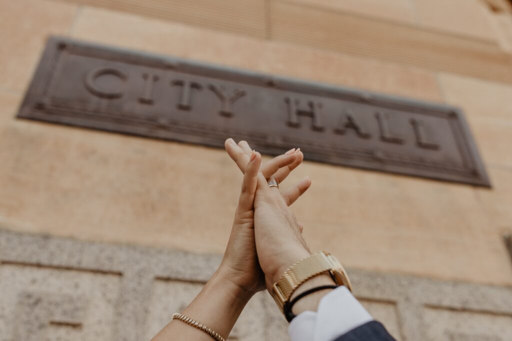 Couple holding hands in front of the Buffalo, NY City Hall sign after their wedding ceremony downtown taken by Jessy Herman Photo