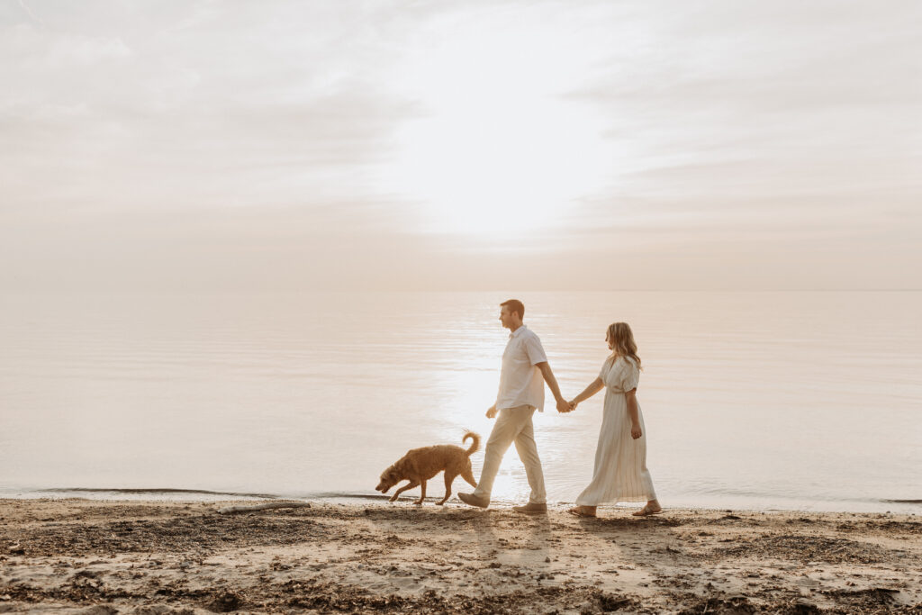 Couple walks on beach during engagement session on Lake Erie in Buffalo, NY with dog photographed by Jessy Herman Photo
