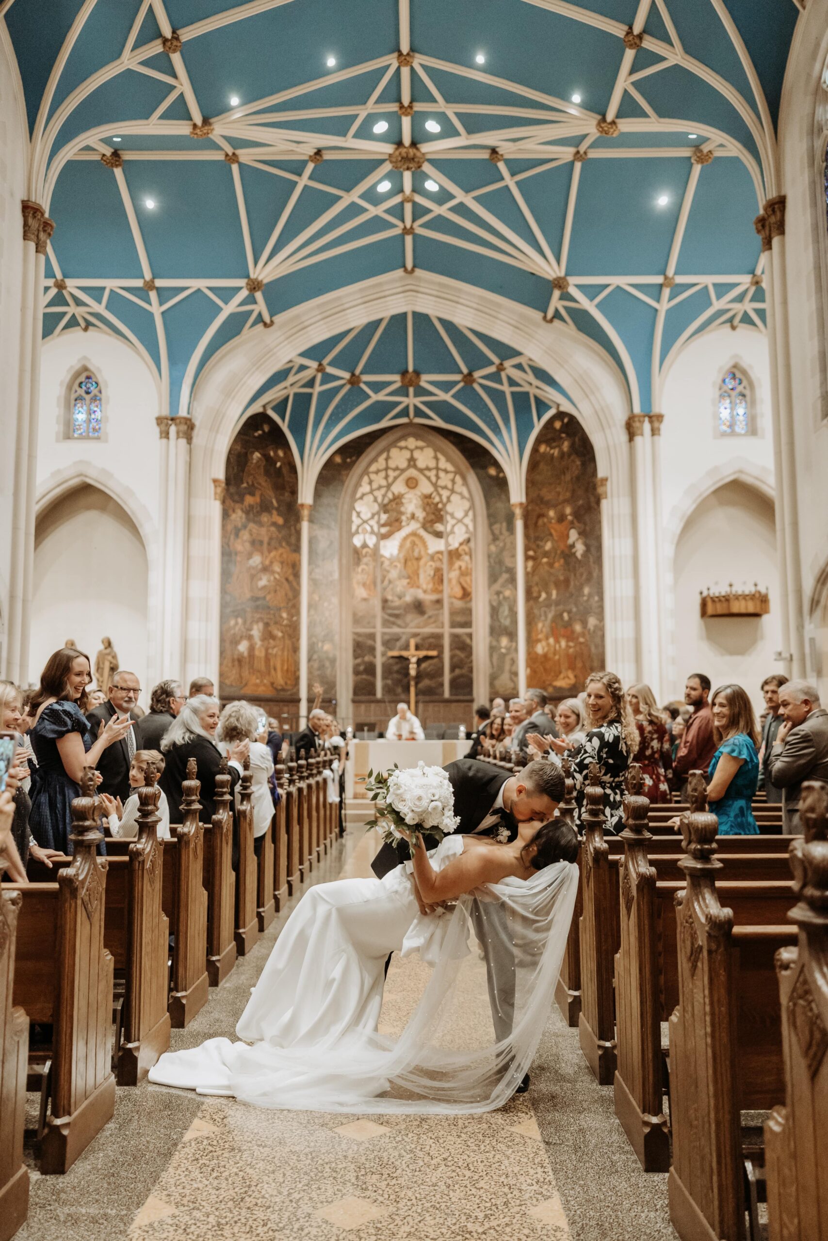 Photo of bride and groom dip kissing down the church aisle