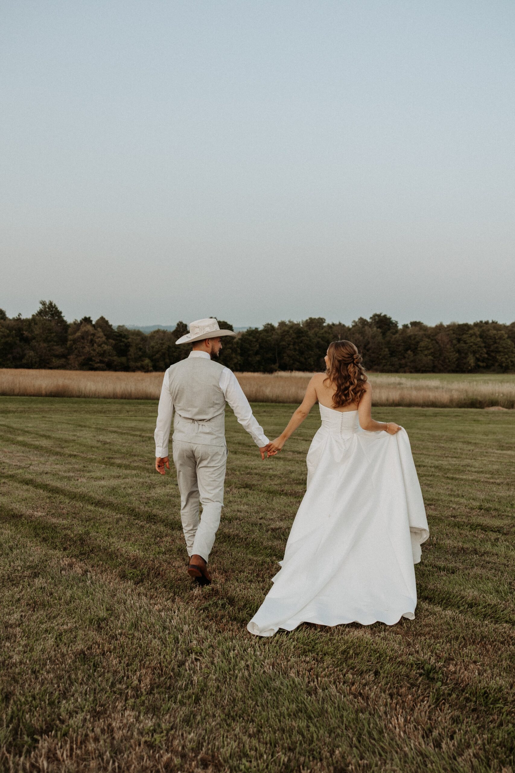 Bride and Groom walk at sunset at Notting Hill Farm in Wales, NY