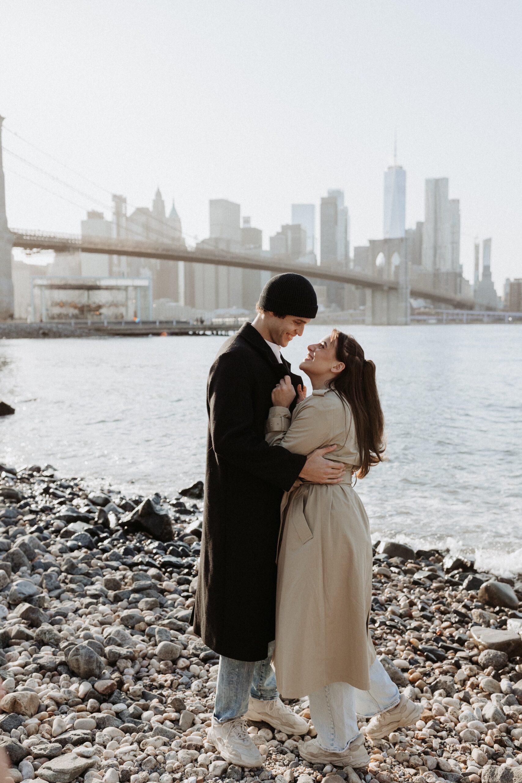 Engaged couple hugging close with NYC skyline in the background photographed by Jessy Herman Photo